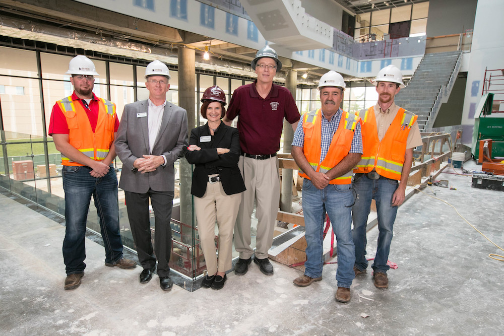 David Meinert, center, wearing maroon, stands inside Glass Hall with College of Business Dean Stephanie Bryant amid renovation work. Meinert is taking over in an interim capacity.
