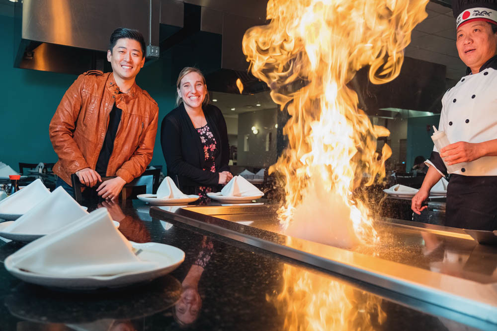 ASIAN FLARE: Co-owner Cosmo Kwon, HR Manager Megan Morano and Nixa head chef Jay Tan show off a teppanyaki grill at Hinode Japanese Steakhouse in Nixa.