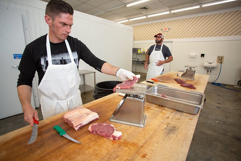 Nick Smith, left, weighs a steak while preparing cuts of beef at American Meat Co., which is keeping shorter operating hours amid supply chain issues.