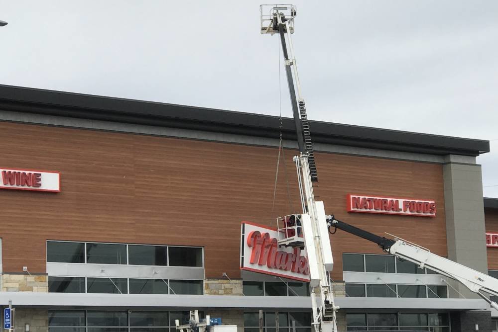 Crews remove Lucky's Market signage on March 31 as Natural Grocers prepares to enter Glenstone Marketplace.