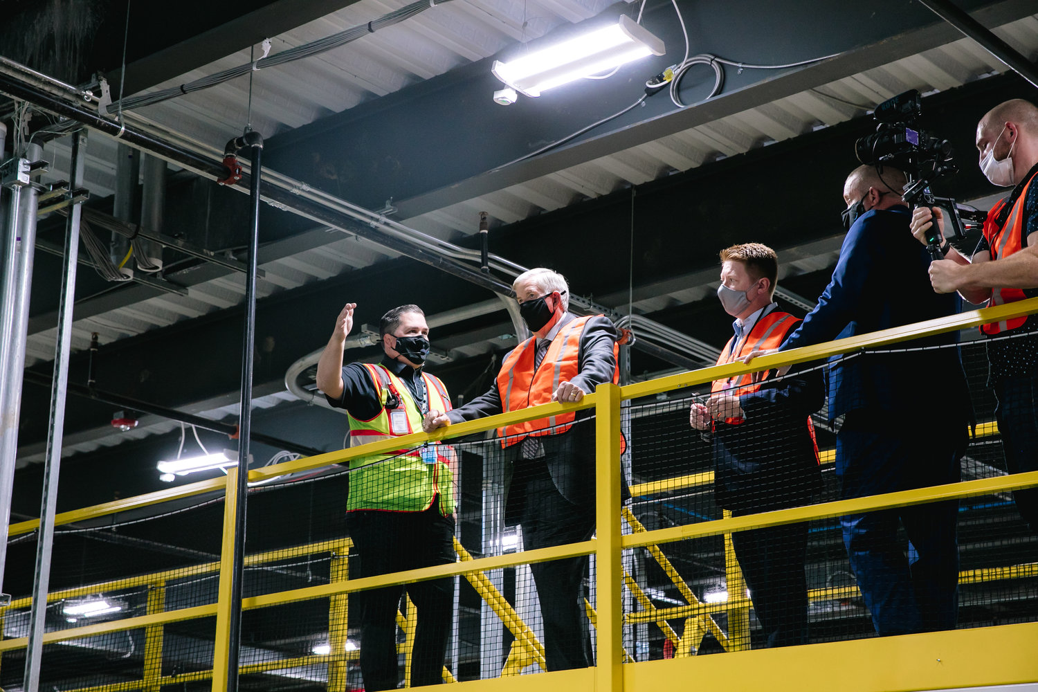 Far left, Andrew Lee, general manager of the Republic fulfillment center, shows the operations floor to Gov. Mike Parson. 