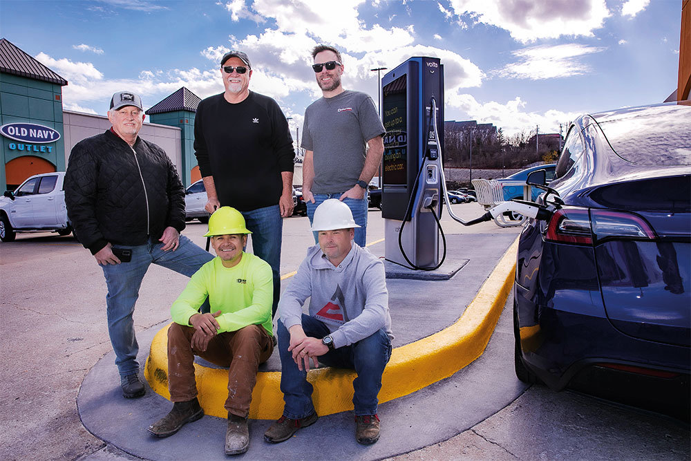 With a newly installed electrical vehicle charger at Branson's Tanger Outlet are Dynamic EVC representatives (from left, standing) John Lorenz, partner; Larry Schmitt, managing partner; Micah Battaglia, general manager; (seated) Martin Medellin, construction superintendent; and Dusty Armstrong, project manager.
