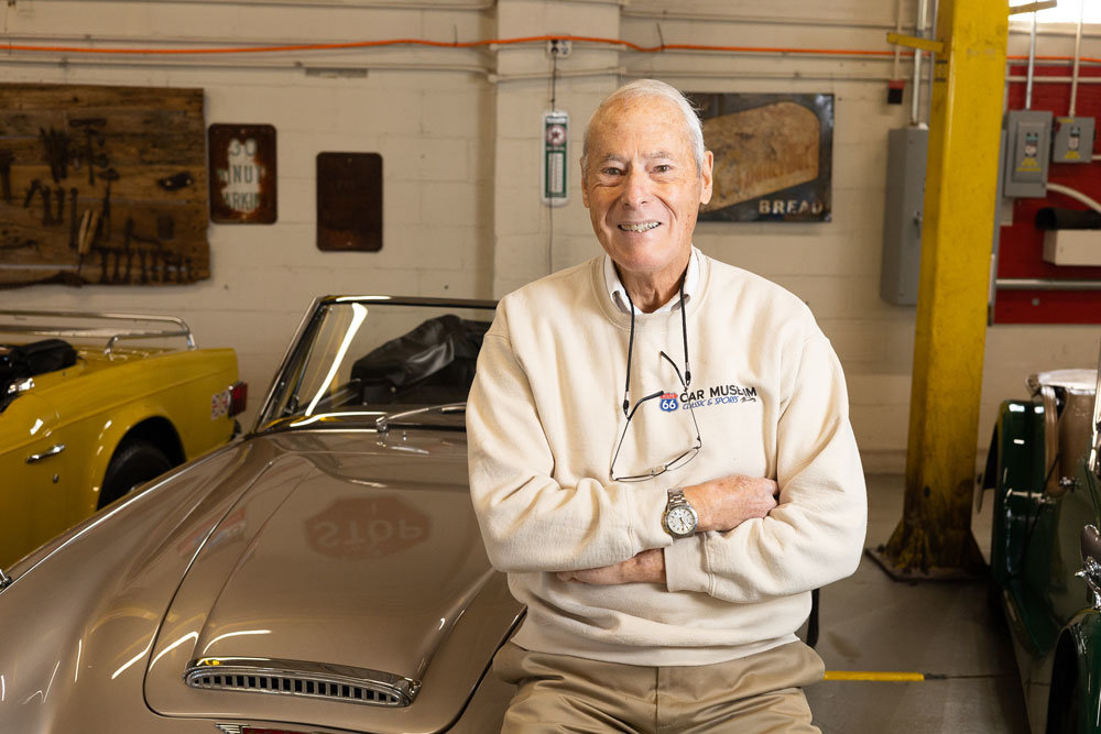 CAR COLLECTOR: Guy Mace, standing beside an Austin Healey 3000, says he owns roughly 80 vehicles at the Route 66 Car Museum he opened in 2016.