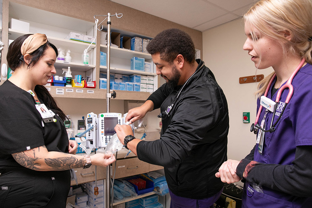 CLASSROOM ACTIVITY: Multiple health care degrees are being added at Southwest Baptist University because of an expanded partnership with Mercy. Mercy nurse Courtney Biber, left, aids SBU students Jordan Gaskins and McKenna Pace as they connect an IV tubing line.